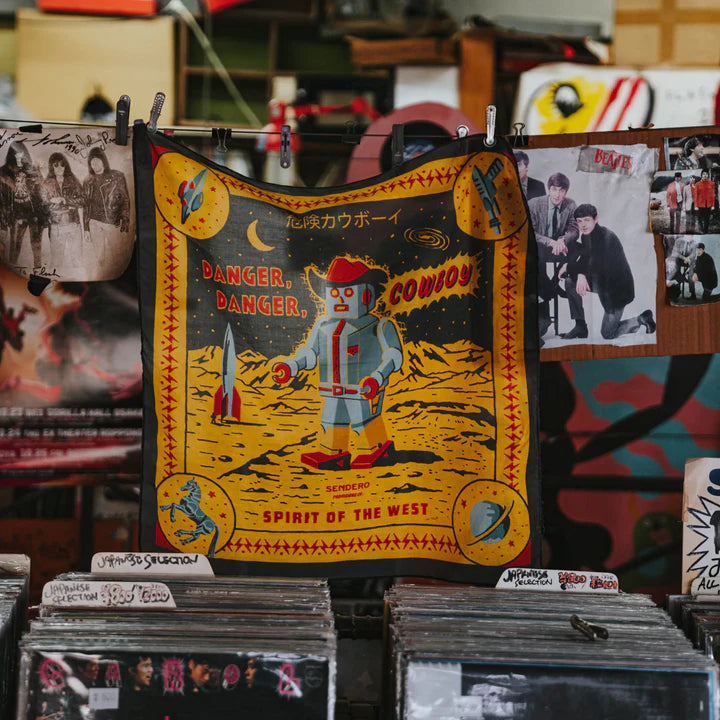 Vintage-style poster with cowboy robot design on a rack with other posters in the background